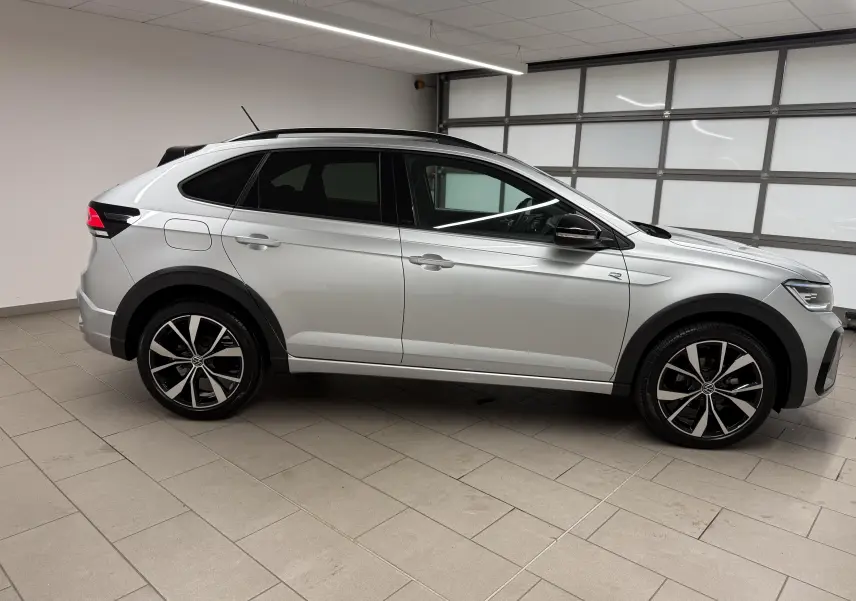 Volkswagen Taigo 2025 en profil côté gauche, peinture argent métallisée avec toit noir et jantes alliage 18 pouces.