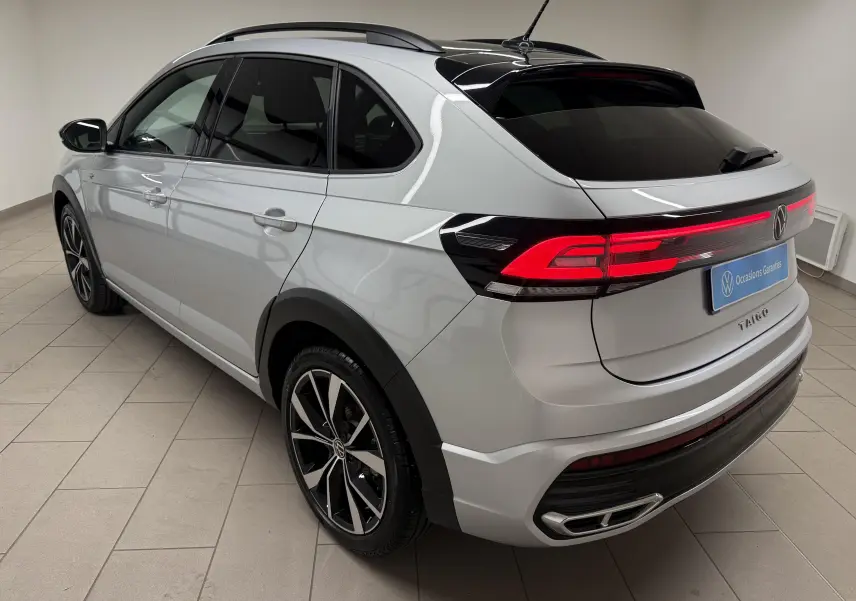 Vue 3/4 arrière droite d'un Volkswagen Taigo 1.5 TSI R-Line 2025 argent métallisé avec toit noir et jantes 18 pouces.