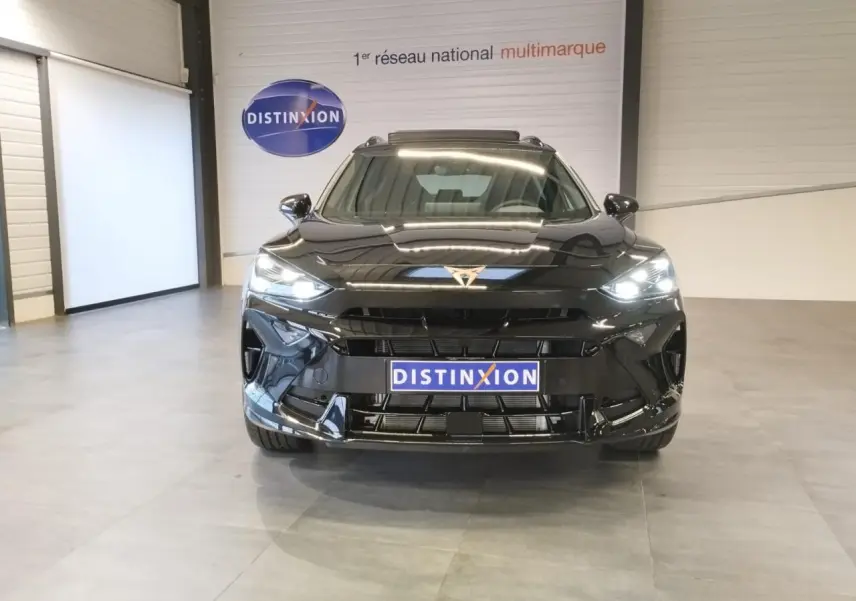 Vue frontale d'une CUPRA Formentor noire métal avec phares allumés et logo CUPRA lumineux au centre du capot.