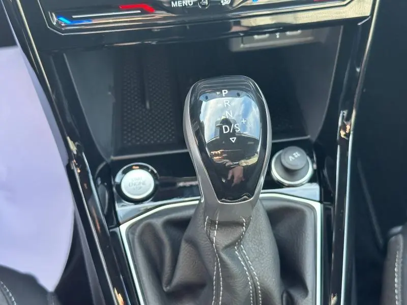 Le levier de vitesses automatique noir brillant du Volkswagen T-Cross argenté, vu de dessus dans l'habitacle.