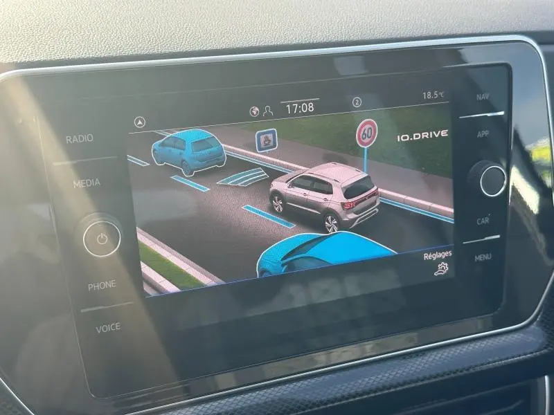Écran tactile intérieur montrant l'aide à la conduite avec un Volkswagen T-Cross argenté vu de trois quarts arrière droit.
