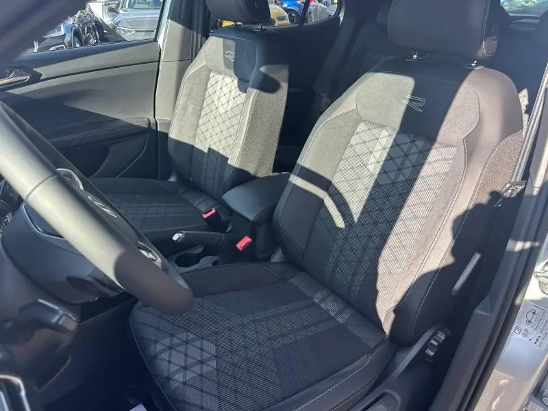 Vue intérieure côté conducteur du Volkswagen T-Cross argenté 2026, sièges avant en tissu R-Line gris/noir avec surpiqûres distinctives.