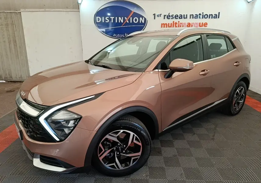 KIA Sportage beige vue 3/4 avant droit, avec phares LED en forme de flèche et jantes alliage distinctives.