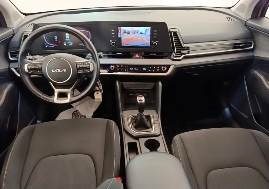Vue intérieure avant du Kia Sportage 2022 avec tableau de bord numérique et boîte manuelle noire.