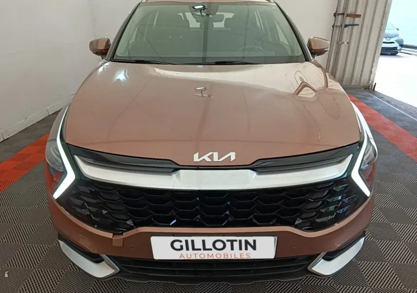Vue avant d’un KIA Sportage beige 2022 avec calandre noire et feux diurnes LED en forme de V.