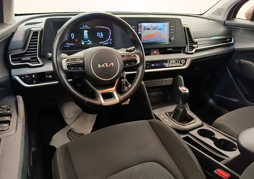 Vue intérieure du poste de conduite du Kia Sportage 2022 avec volant cuir multifonctions et écran tactile central affichant la caméra de recul.