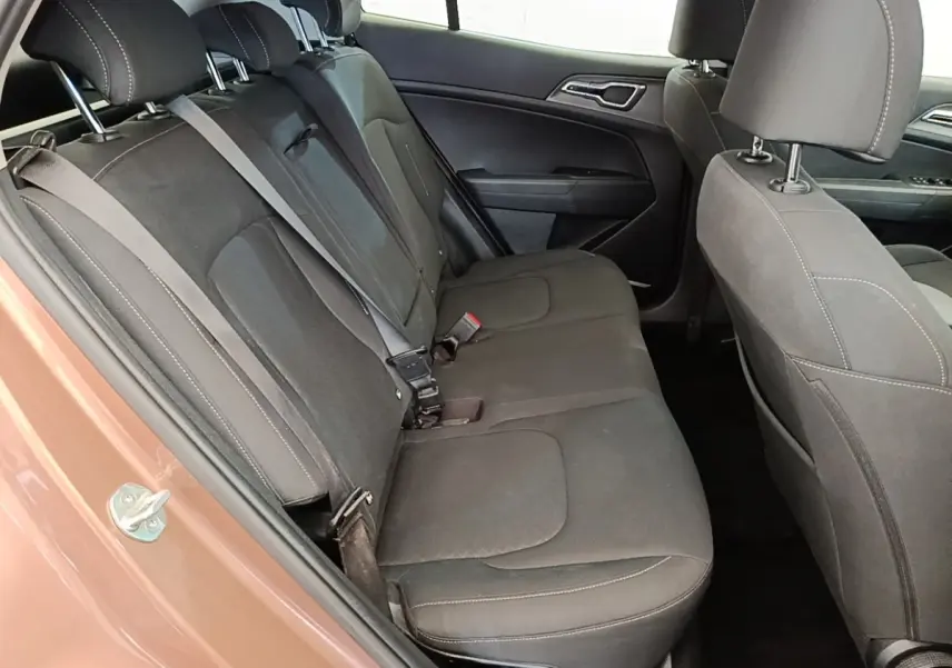 Vue intérieure côté arrière gauche du Kia Sportage beige 2022 montrant la banquette arrière en tissu gris foncé avec ceintures de sécurité.