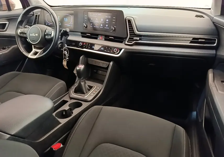 Intérieur noir du Kia Sportage 2022 vu côté conducteur, avec volant cuir multifonctions et boîte manuelle.