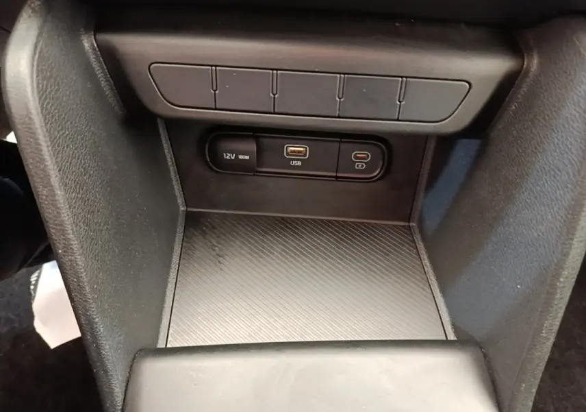 Vue rapprochée de la console centrale du Kia Sportage beige 2022, avec prises 12V et USB visibles.