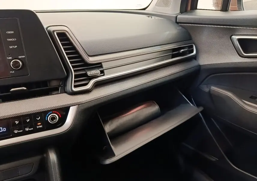 Intérieur du Kia Sportage 2022, vue côté passager sur tableau de bord et boîte à gants ouverte noire.
