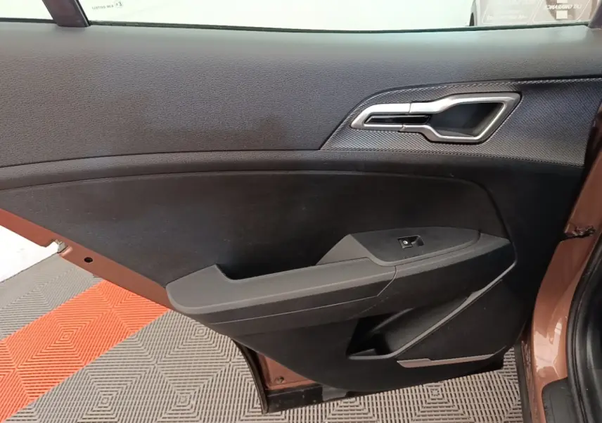Vue rapprochée de la porte arrière gauche beige du Kia Sportage 2022, avec poignée intérieure chromée et panneau noir.