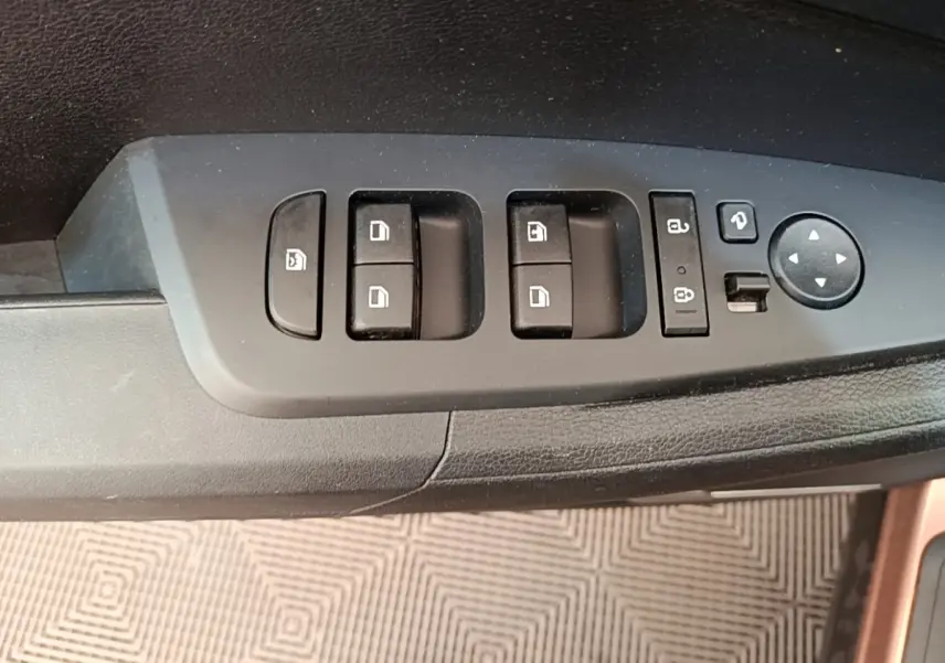 Gros plan sur les commandes de lève-vitres et rétroviseurs côté conducteur du Kia Sportage beige 2022.