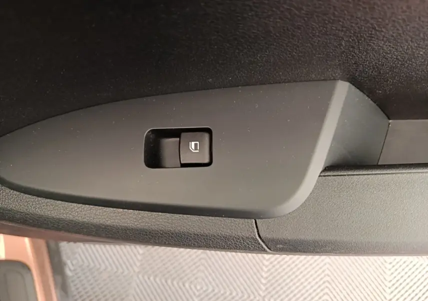 Bouton de verrouillage des vitres sur la porte intérieure noire d’un KIA SPORTAGE beige, vue en gros plan.