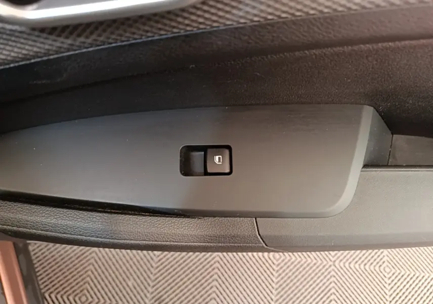 Gros plan sur le bouton de verrouillage électrique des vitres sur la porte intérieure côté conducteur du Kia Sportage beige 2022.