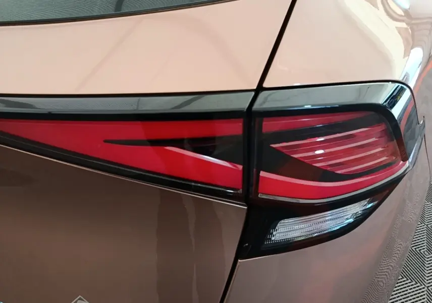 Gros plan sur le feu arrière droit rouge et blanc d’un KIA SPORTAGE beige 2022, soulignant ses lignes modernes.