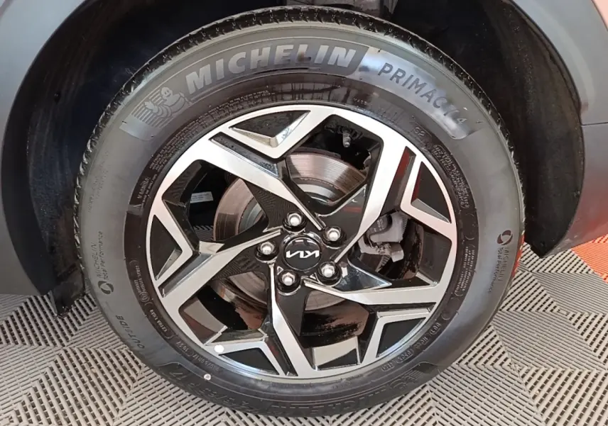 Gros plan sur la roue avant droite d’un KIA Sportage beige, jante alliage noire et argent avec pneu Michelin.
