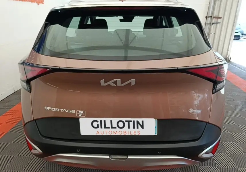 Vue arrière d’un KIA Sportage beige 2022 avec feux arrière LED et logo moderne sur hayon.
