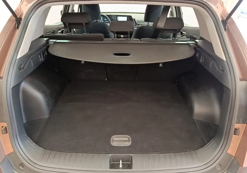 Coffre ouvert vu de l'arrière d'un KIA SPORTAGE beige 2022, avec cache-bagages et banquette arrière rabattable.