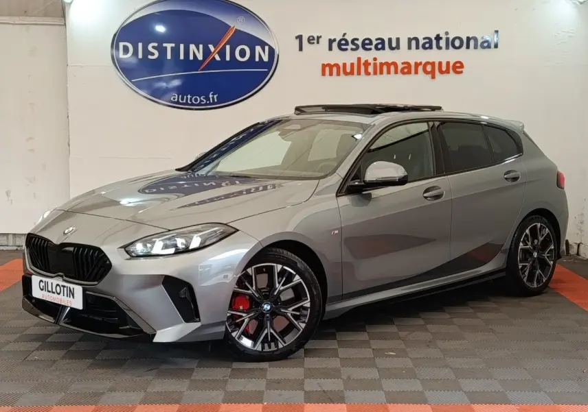 BMW Série 1 120 DKG7 M Sport gris clair vue 3/4 avant droit avec jantes noires et étriers rouges visibles