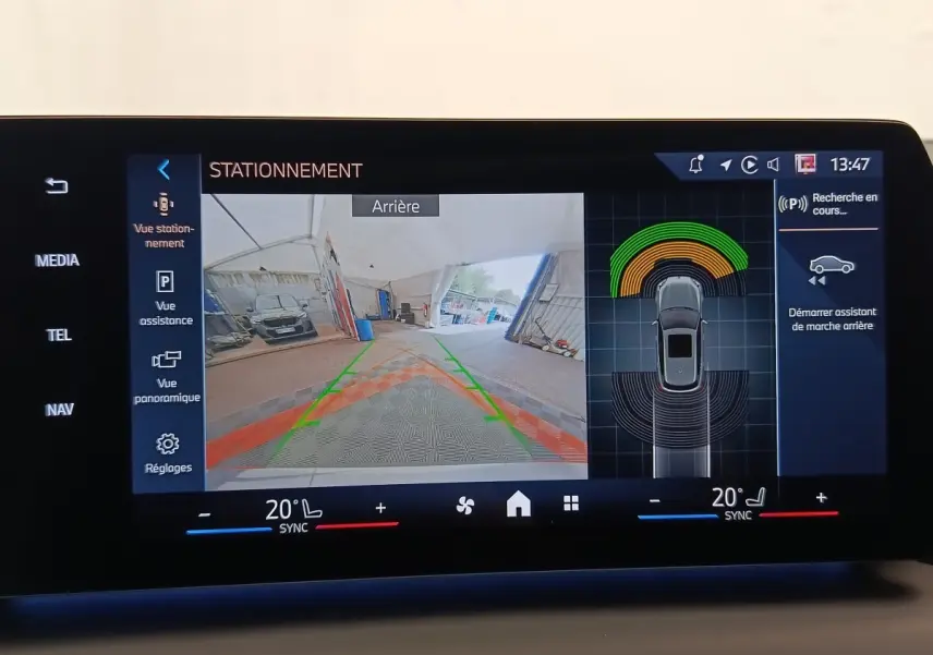 Écran tactile montrant la caméra de recul et l’aide au stationnement d’une BMW Série 1 gris clair, vue arrière.