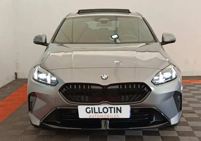 Vue avant d'une BMW Série 1 120 DKG7 M Sport gris clair avec phares LED allumés et calandre noire distinctive.