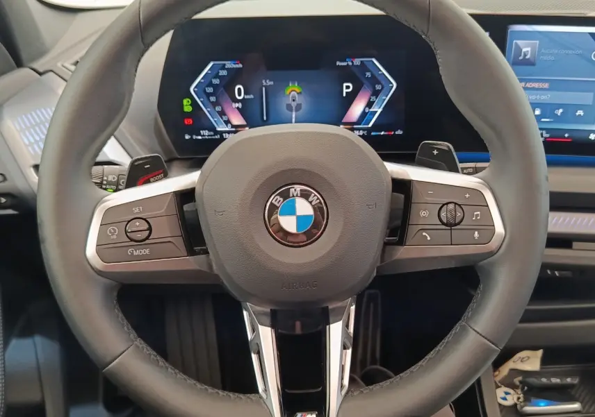 Vue rapprochée du volant cuir M Sport et du combiné numérique de la BMW Série 1 120 DKG7 hybride 2025.