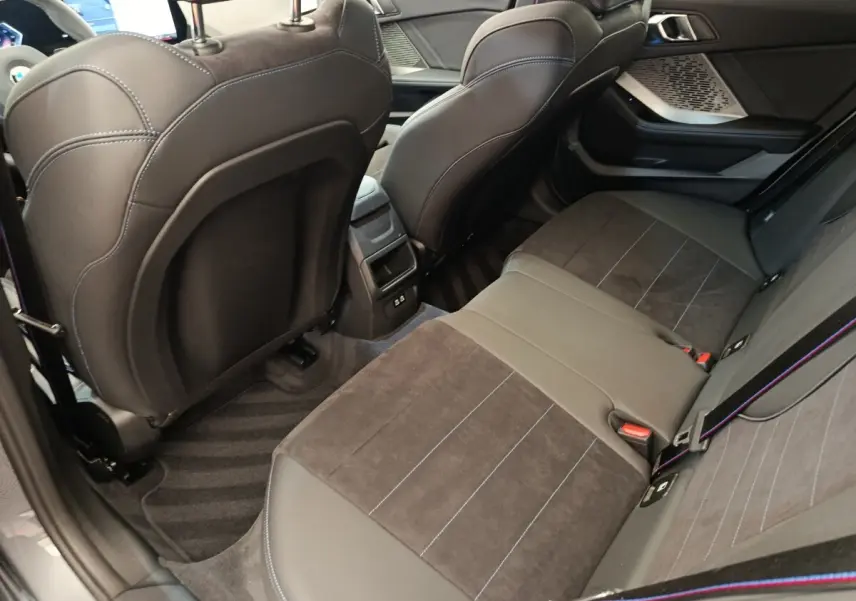 Vue intérieure arrière côté droit de la BMW Série 1 120 DKG7 M Sport 2025 avec sièges en cuir et alcantara noirs.
