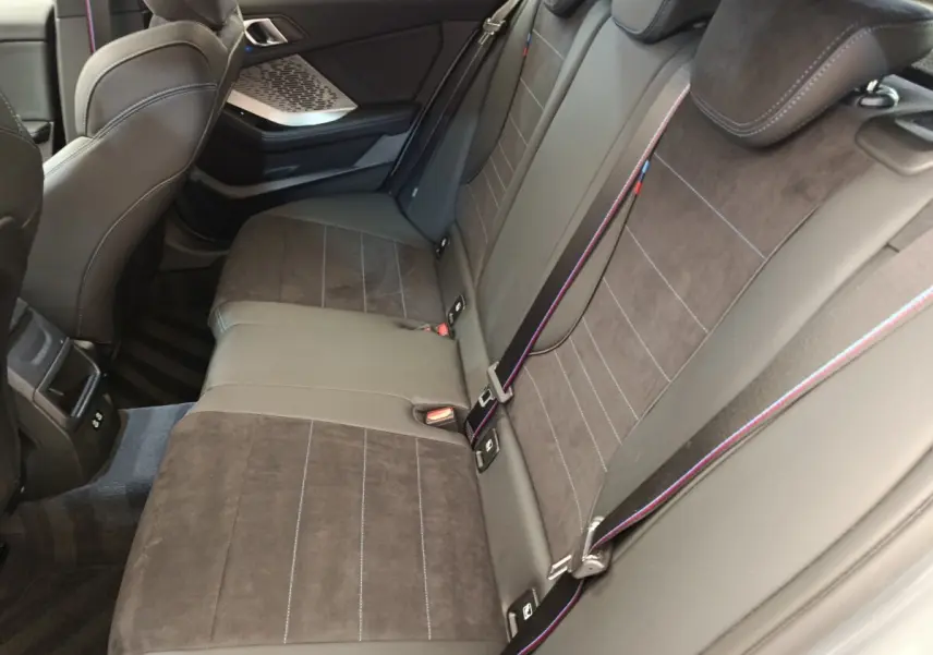 Vue intérieure côté droit sur la banquette arrière en cuir et alcantara gris foncé avec surpiqûres tricolores BMW M Sport.