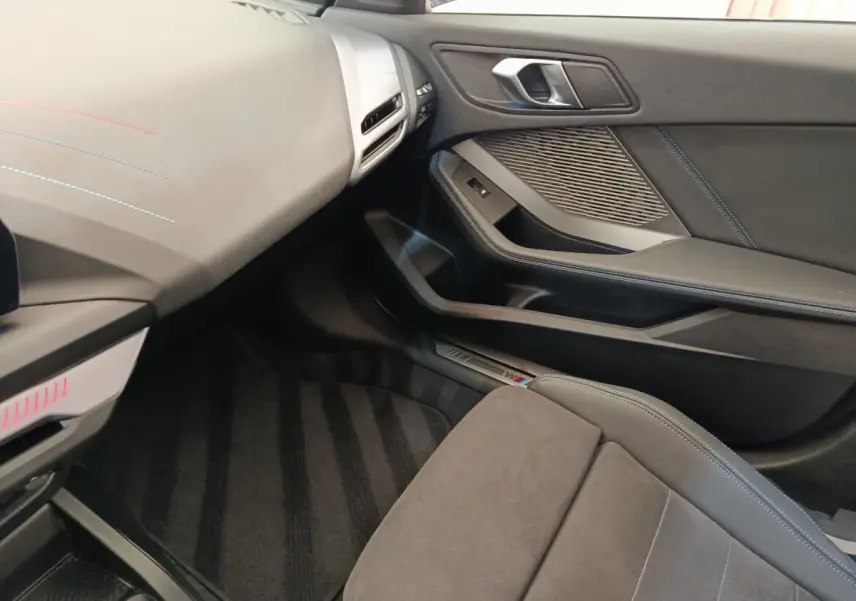 Intérieur côté passager de la BMW Série 1 120 DKG7 M Sport 2025, avec sellerie grise et finitions M Sport visibles.