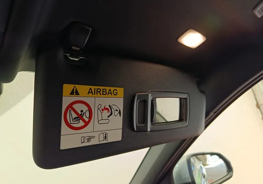 Détail du pare-soleil côté conducteur avec miroir intégré et avertissement airbag dans une BMW Série 1 gris clair.