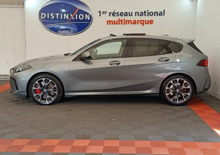 BMW Série 1 120 DKG7 M Sport gris clair vue de profil côté gauche avec jantes sport et étriers rouges visibles.