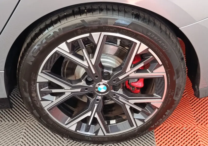 Gros plan sur la roue avant droite d'une BMW Série 1 120 DKG7 M Sport gris clair avec étrier de frein rouge.