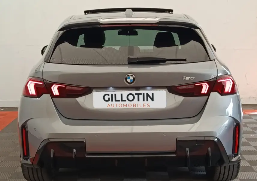 Vue arrière d'une BMW Série 1 120 DKG7 M Sport gris clair avec feux LED allumés et diffuseur noir sportif.