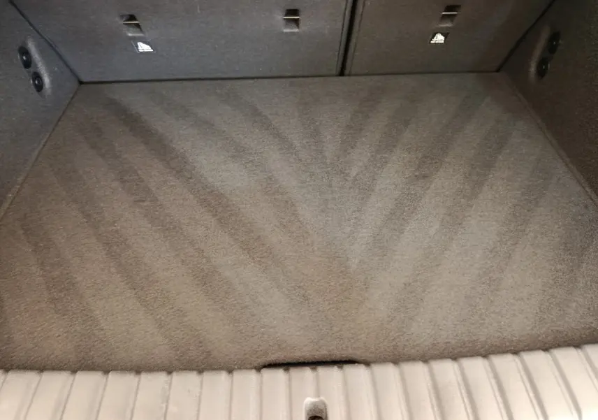 Coffre vide en moquette grise de BMW Série 1 120 DKG7 M Sport, vue intérieure depuis l'ouverture arrière.