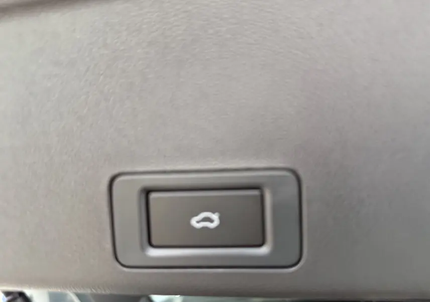 Bouton intérieur noir avec symbole blanc d'ouverture de coffre, sur tableau de bord du JAECOO J7 PHEV gris olive.