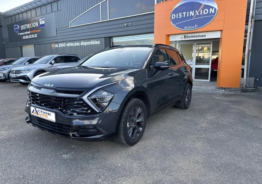KIA Sportage gris Eclipse métallisé vu en 3/4 avant droit devant un garage Distinxion.