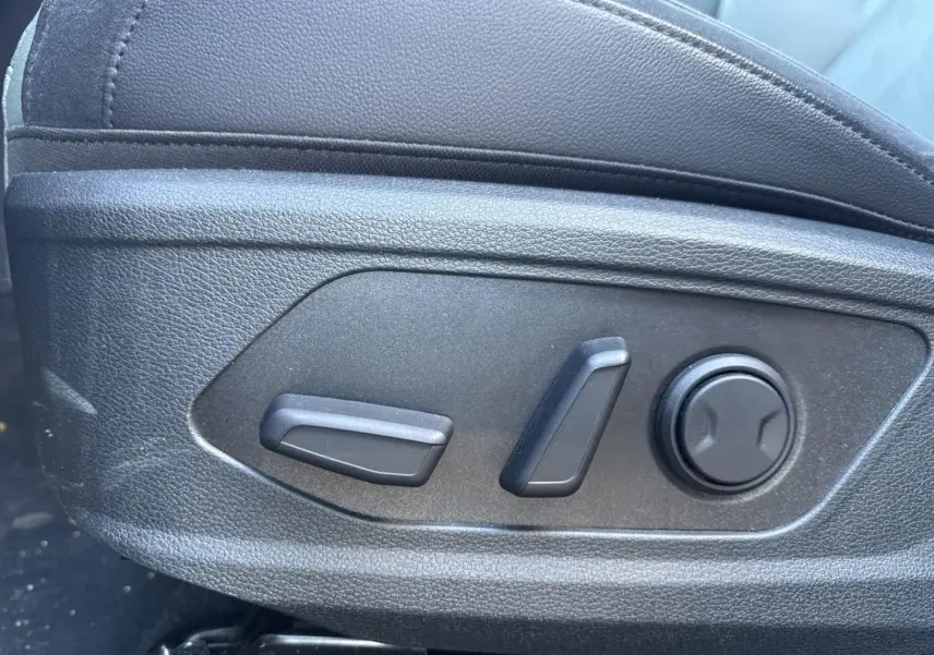 Gros plan sur les commandes de réglage électrique du siège conducteur noir dans un KIA SPORTAGE gris Eclipse Métallisée 2025.