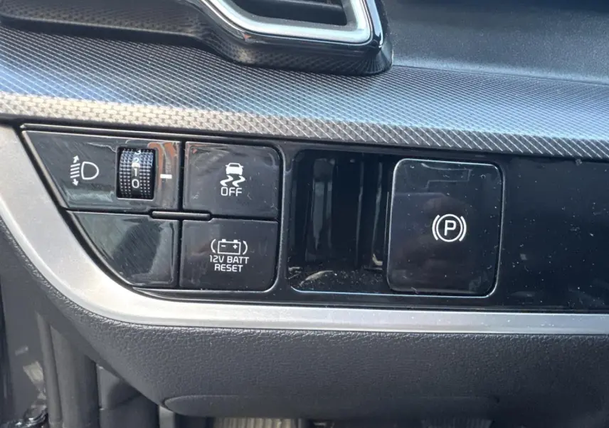 Détail des commandes de tableau de bord noir et gris dans un Kia Sportage 2025 hybride.