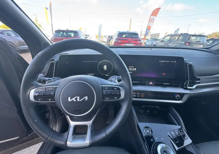 Vue intérieure centrée sur le volant cuir multifonction et l’écran tactile du Kia Sportage gris Eclipse 2025.