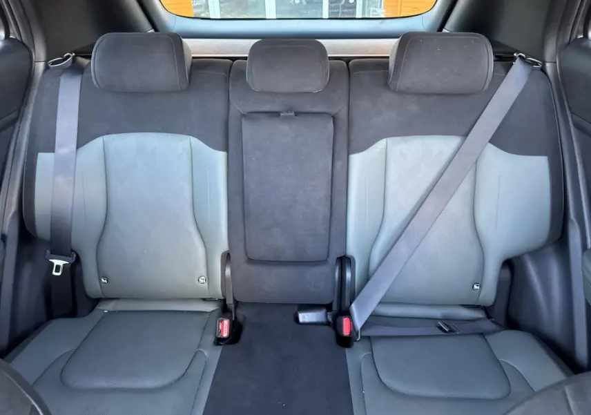 Vue arrière intérieure du Kia Sportage 2025 montrant la banquette 3 places en cuir suédine vert pin et gris clair.