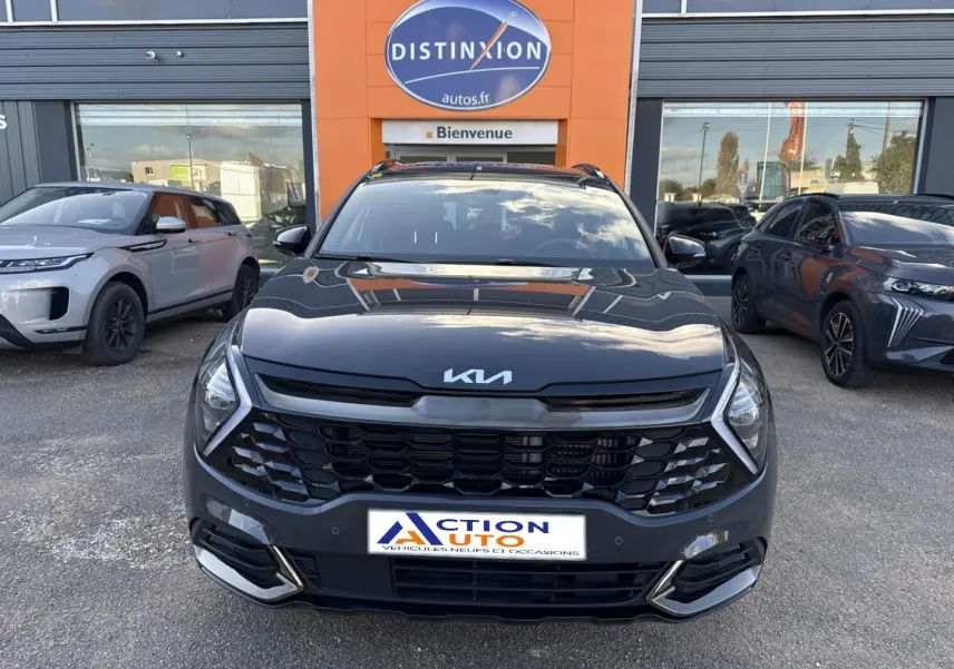 Vue avant d'un Kia Sportage 2025 gris Eclipse métallisé avec calandre noire et phares LED, devant un concessionnaire.
