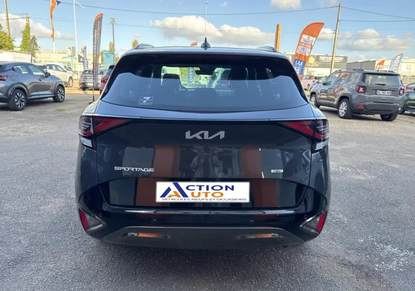 Vue arrière d'un KIA Sportage gris Eclipse métallisé 2025 avec feux LED et logo central sur un parking extérieur.