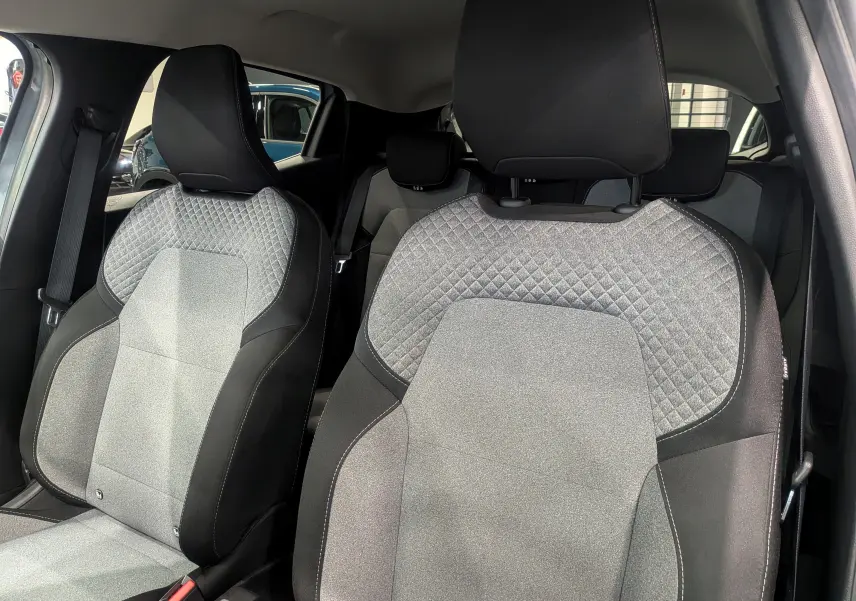 Gros plan sur les sièges avant en tissu gris clair et noir de la Renault Clio V Blue dCi 100 Evolution 2025.