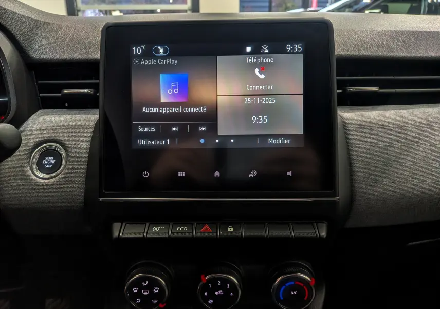 Tableau de bord de Renault Clio V 2025 avec écran tactile central affichant Apple CarPlay, boutons de commande et bouton start/stop.