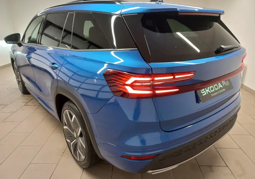 Vue 3/4 arrière droite du Skoda Kodiaq 2024 bleu RS avec feux LED allumés et jantes alliage 20 pouces anthracite.