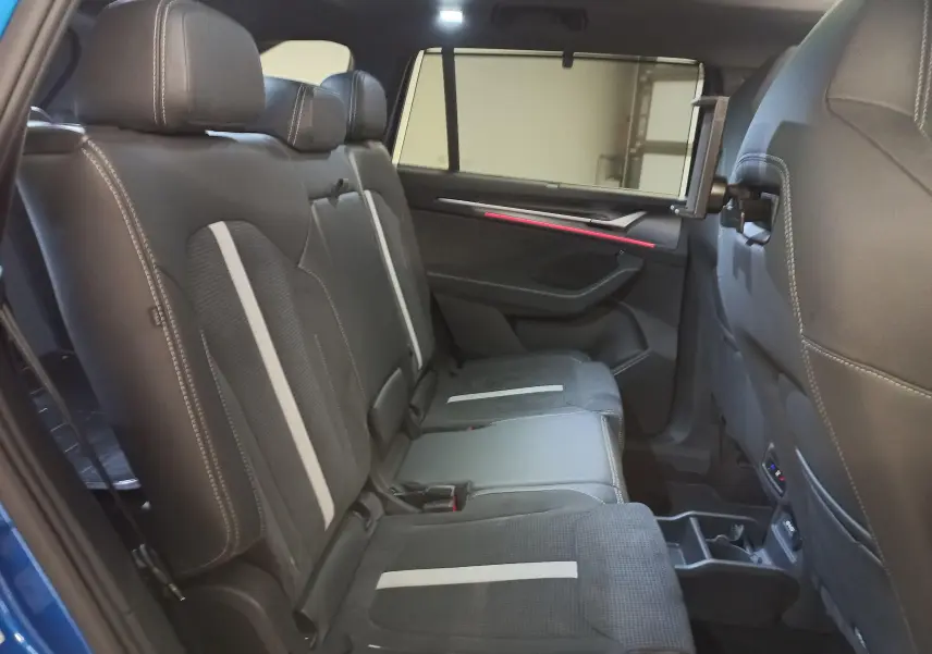 Vue intérieure côté droit des sièges arrière en cuir noir avec bandes grises et tablette intégrée sur un Skoda Kodiaq Bleu RS 2024.