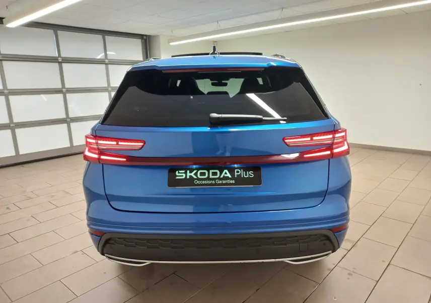 Vue arrière du Skoda Kodiaq 2024 Bleu RS avec feux LED reliés par un bandeau lumineux rouge dans un garage.