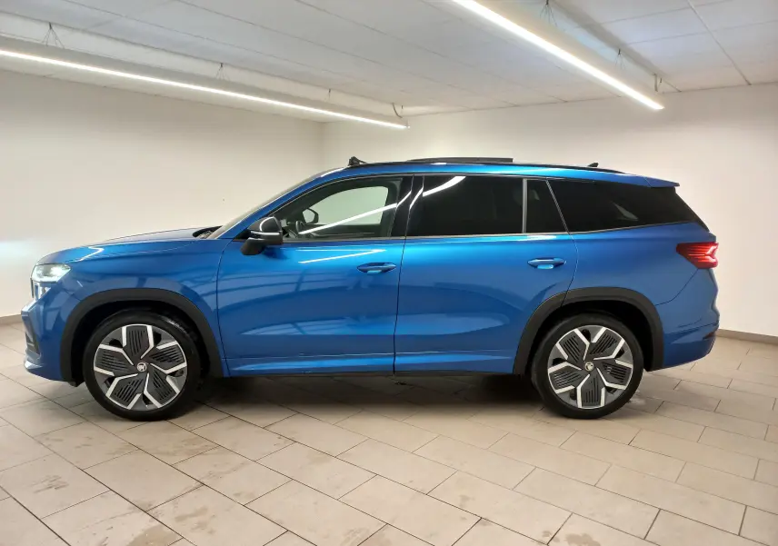 Vue de profil côté gauche d'un Skoda Kodiaq 2024 bleu RS avec jantes alliage 20'' Rila anthracite et toit panoramique.