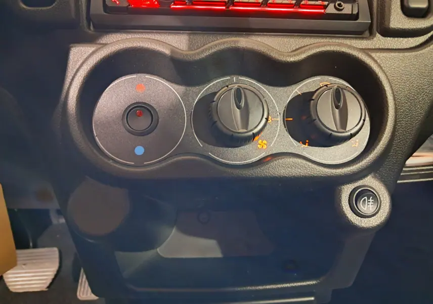 Gros plan sur les commandes de climatisation noires du tableau de bord de l’AIXAM MINAUTO E chic vert, côté conducteur.