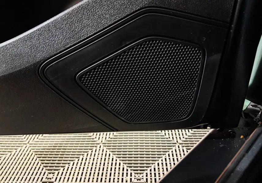 Gros plan sur le haut-parleur intégré à la porte côté conducteur d'une Aixam Minauto E chic 2026, intérieur noir.